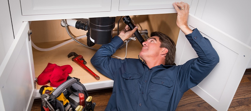 Highly experienced commercial plumber inspecting a sink.