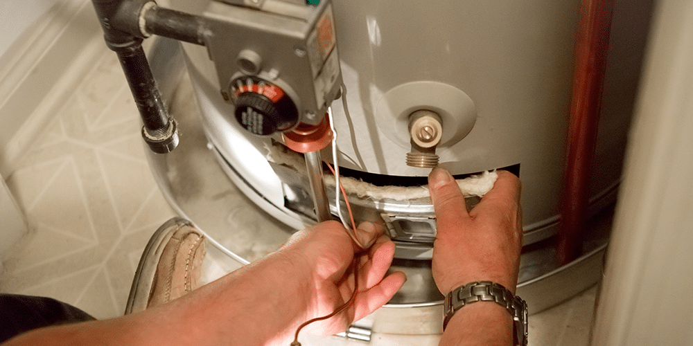 Water Heater Replacement Man checking a water heater to determine if a replacement is needed.