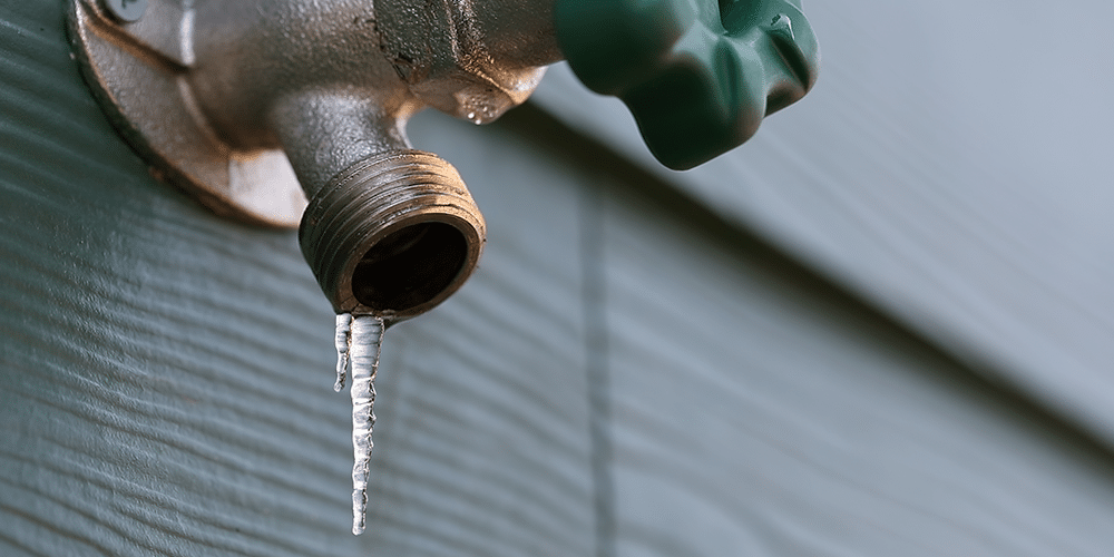 Frozen spigot on the outside of a house in winter.