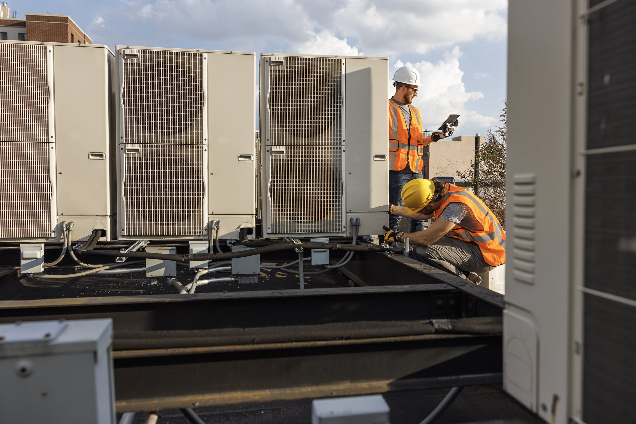 HVAC technicians check rooftop air conditioner units and log tHVAC technicians check rooftop air conditioner units.he result with a portable computer.
