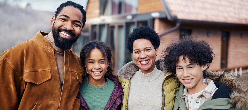Furnaces Mother, father, and two kids smile and pose outside their home on a crisp winter day.