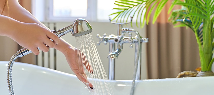 Homeowner tests the temperature of the water coming out of their home hand shower.